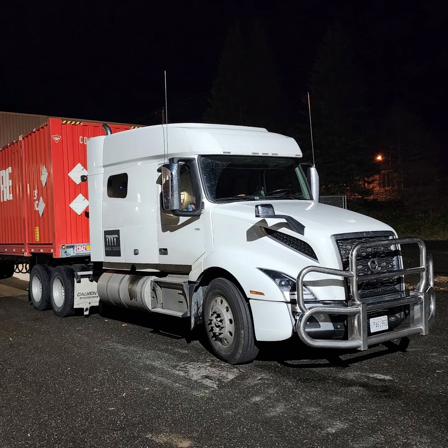 Mancini Trucking truck at night with a sea container